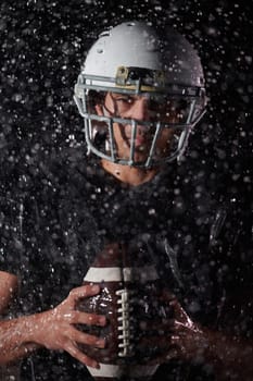 American Football Field: Lonely Athlete Warrior Standing on a Field Holds his Helmet and Ready to Play. Player Preparing to Run, Attack and Score Touchdown. Rainy Night with Dramatic Fog, Blue Light.