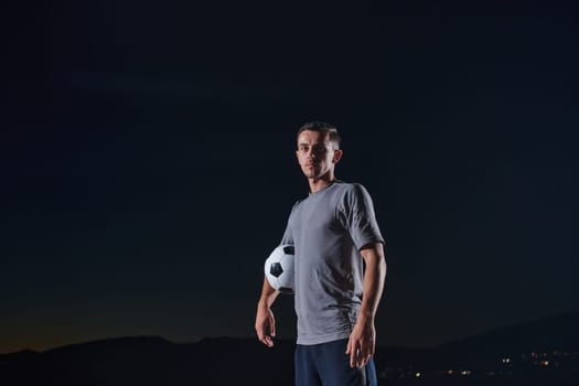 Portrait of a young handsome soccer player man on a street playing with a football ball