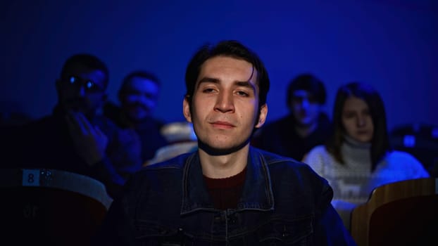 Audience at theatre or cinema. Media. Portrait of a man and silhouettes behind applauding