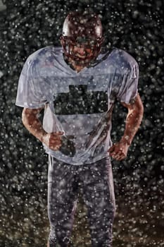 American Football Field: Lonely Athlete Warrior Standing on a Field Holds his Helmet and Ready to Play. Player Preparing to Run, Attack and Score Touchdown. Rainy Night with Dramatic Fog, Blue Light.