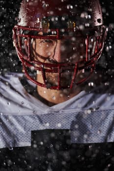 American Football Field: Lonely Athlete Warrior Standing on a Field Holds his Helmet and Ready to Play. Player Preparing to Run, Attack and Score Touchdown. Rainy Night with Dramatic Fog, Blue Light.