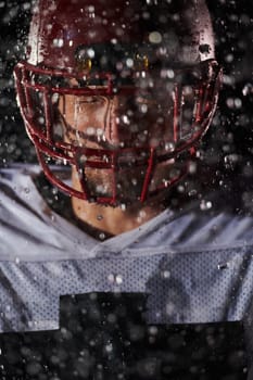 American Football Field: Lonely Athlete Warrior Standing on a Field Holds his Helmet and Ready to Play. Player Preparing to Run, Attack and Score Touchdown. Rainy Night with Dramatic Fog, Blue Light.