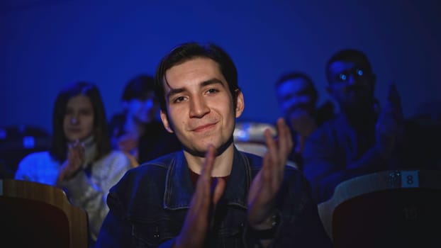 Young man is watching theatrical performance. Media. Man is watching theatrical performance in place. Spectator illuminated by spotlight at theatrical performance.