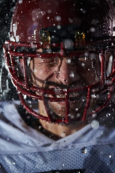 American Football Field: Lonely Athlete Warrior Standing on a Field Holds his Helmet and Ready to Play. Player Preparing to Run, Attack and Score Touchdown. Rainy Night with Dramatic Fog, Blue Light.