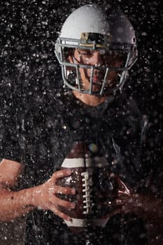 American Football Field: Lonely Athlete Warrior Standing on a Field Holds his Helmet and Ready to Play. Player Preparing to Run, Attack and Score Touchdown. Rainy Night with Dramatic Fog, Blue Light.