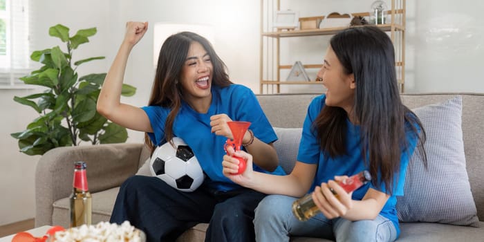 Lesbian Soccer or Sport fans emotionally watching game in the living room.