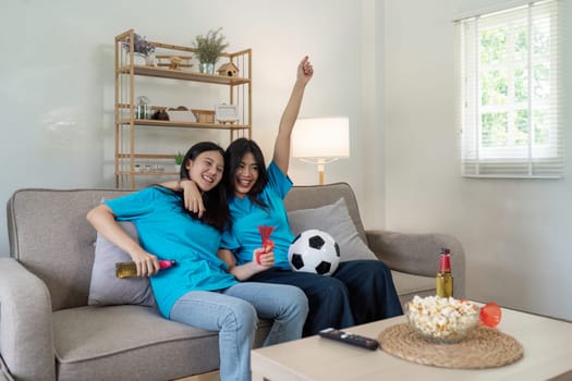 Lesbian Soccer or Sport fans emotionally watching game in the living room.