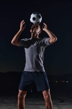 Portrait of a young handsome soccer player man on a street playing with a football ball.