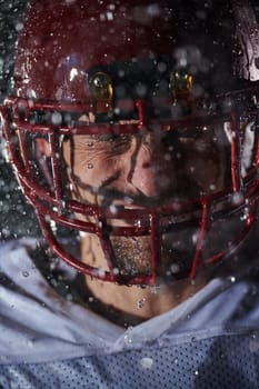 American Football Field: Lonely Athlete Warrior Standing on a Field Holds his Helmet and Ready to Play. Player Preparing to Run, Attack and Score Touchdown. Rainy Night with Dramatic Fog, Blue Light.