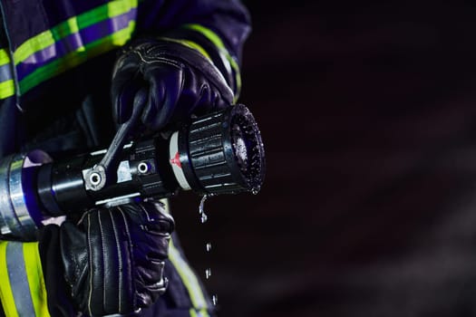 Firefighter using a water hose to eliminate a fire hazard. Team of firemen in the dangerous rescue mission