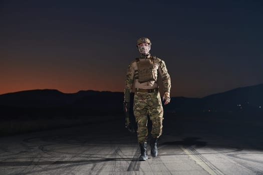 A professional soldier in full military gear striding through the dark night as he embarks on a perilous military mission.