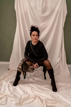 A woman is sitting on a chair with her legs crossed and wearing a black dress. She is holding a handbag and has a necklace around her neck. Concept of elegance and sophistication