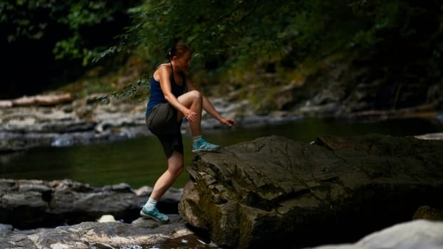 Young caucasian girl walking carefully on stony path and river. Creative. Concept of active lifestyle and hiking