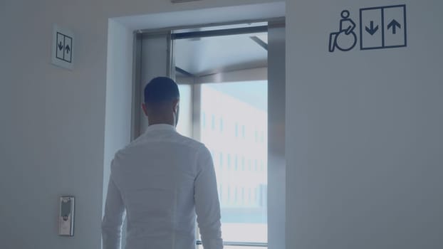 Man enters elevator with window. Media. Rear view of man entering light elevator. Modern beautiful elevator with panoramic windows.