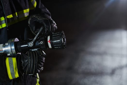 Firefighter using a water hose to eliminate a fire hazard. Team of firemen in the dangerous rescue mission