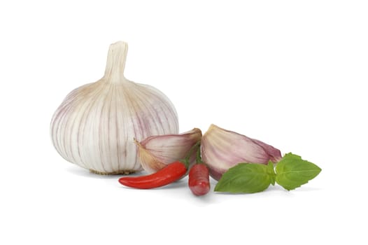 Whole garlic bulb with garlic cloves close to two red chili peppers and a sprig of basil leaves isolated on white background
