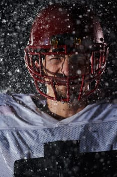 American Football Field: Lonely Athlete Warrior Standing on a Field Holds his Helmet and Ready to Play. Player Preparing to Run, Attack and Score Touchdown. Rainy Night with Dramatic Fog, Blue Light.