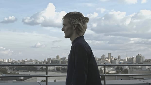 Young man on roof of building. Stock. Young man behaves strangely while on roof of building. Man on terrace of high-rise building on summer day.