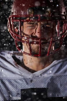 American Football Field: Lonely Athlete Warrior Standing on a Field Holds his Helmet and Ready to Play. Player Preparing to Run, Attack and Score Touchdown. Rainy Night with Dramatic Fog, Blue Light.