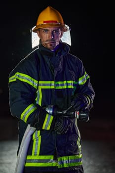 Firefighter using a water hose to eliminate a fire hazard. Team of female and male firemen in dangerous rescue mission