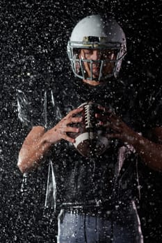 American Football Field: Lonely Athlete Warrior Standing on a Field Holds his Helmet and Ready to Play. Player Preparing to Run, Attack and Score Touchdown. Rainy Night with Dramatic Fog, Blue Light.