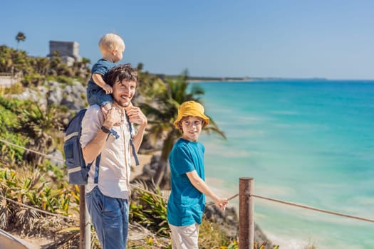 Father and two sons tourists enjoying the view Pre-Columbian Mayan walled city of Tulum, Quintana Roo, Mexico, North America, Tulum, Mexico. El Castillo - castle the Mayan city of Tulum main temple.