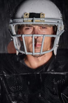 American Football Field: Lonely Athlete Warrior Standing on a Field Holds his Helmet and Ready to Play. Player Preparing to Run, Attack and Score Touchdown. Rainy Night with Dramatic Fog, Blue Light.