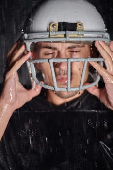 American Football Field: Lonely Athlete Warrior Standing on a Field Holds his Helmet and Ready to Play. Player Preparing to Run, Attack and Score Touchdown. Rainy Night with Dramatic Fog, Blue Light.