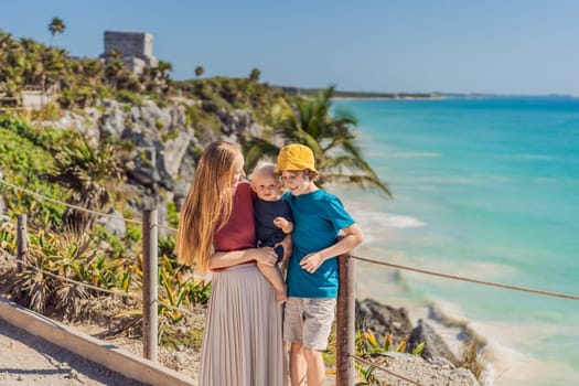 Mother and two sons tourists enjoying the view Pre-Columbian Mayan walled city of Tulum, Quintana Roo, Mexico, North America, Tulum, Mexico. El Castillo - castle the Mayan city of Tulum main temple.