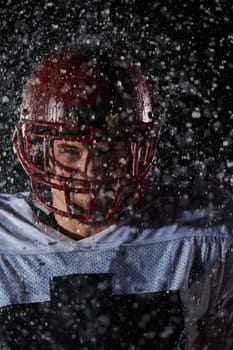 American Football Field: Lonely Athlete Warrior Standing on a Field Holds his Helmet and Ready to Play. Player Preparing to Run, Attack and Score Touchdown. Rainy Night with Dramatic Fog, Blue Light.