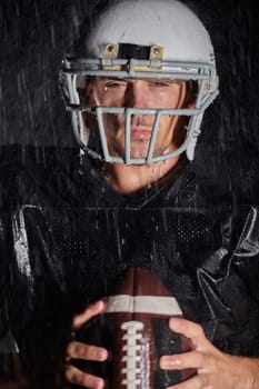 American Football Field: Lonely Athlete Warrior Standing on a Field Holds his Helmet and Ready to Play. Player Preparing to Run, Attack and Score Touchdown. Rainy Night with Dramatic Fog, Blue Light.