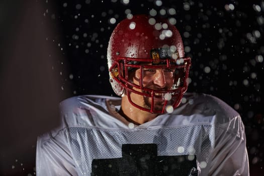 American Football Field: Lonely Athlete Warrior Standing on a Field Holds his Helmet and Ready to Play. Player Preparing to Run, Attack and Score Touchdown. Rainy Night with Dramatic Fog, Blue Light.