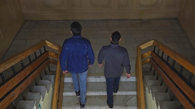 Students walk up stairs of building. Media. Students climb stairs of university. Students inside university walk up stairs.