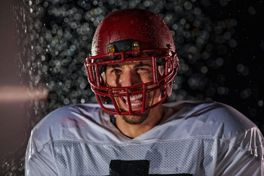 American Football Field: Lonely Athlete Warrior Standing on a Field Holds his Helmet and Ready to Play. Player Preparing to Run, Attack and Score Touchdown. Rainy Night with Dramatic Fog, Blue Light.