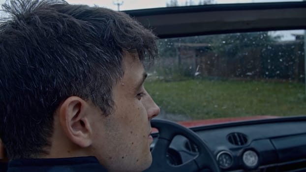 Young couple in a cabriolet car. Stock. Boy and girl enjoy the time in cabriolet on a village house background