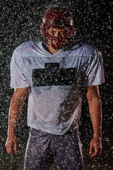 American Football Field: Lonely Athlete Warrior Standing on a Field Holds his Helmet and Ready to Play. Player Preparing to Run, Attack and Score Touchdown. Rainy Night with Dramatic Fog, Blue Light.