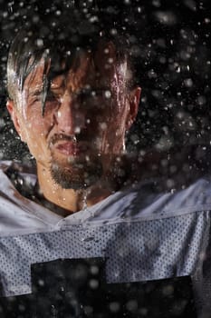 American Football Field: Lonely Athlete Warrior Standing on a Field Holds his Helmet and Ready to Play. Player Preparing to Run, Attack and Score Touchdown. Rainy Night with Dramatic Fog, Blue Light.