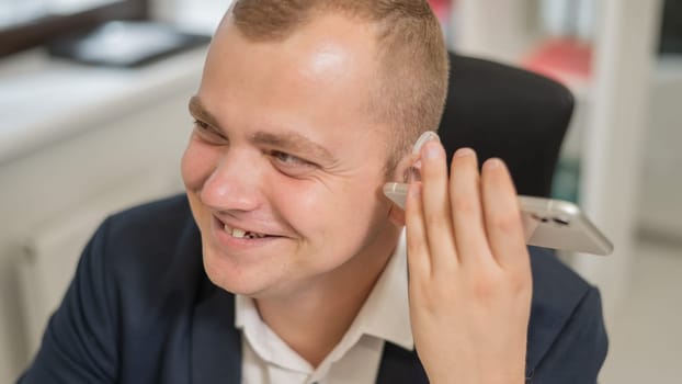 Caucasian man with a hearing aid talking on the phone on speakerphone