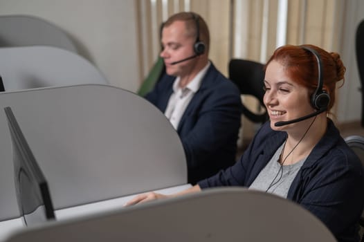 Two friendly call center employees answer customers by phone. Man and woman woman talking on a headset in the office