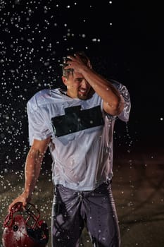 American Football Field: Lonely Athlete Warrior Standing on a Field Holds his Helmet and Ready to Play. Player Preparing to Run, Attack and Score Touchdown. Rainy Night with Dramatic Fog, Blue Light.