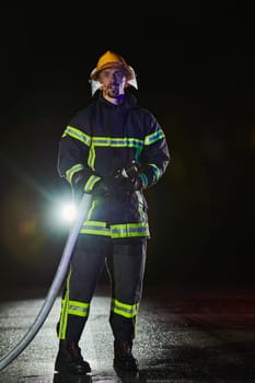 Firefighters using a water hose to eliminate a fire hazard. Team of female and male firemen in dangerous rescue mission