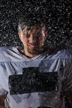 American Football Field: Lonely Athlete Warrior Standing on a Field Holds his Helmet and Ready to Play. Player Preparing to Run, Attack and Score Touchdown. Rainy Night with Dramatic Fog, Blue Light.