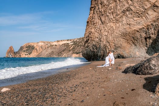 Woman beach white dress flying on Wind. Summer Vacation. A happy woman takes vacation photos to send to friends