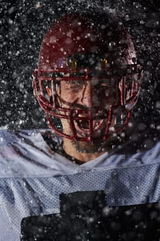 American Football Field: Lonely Athlete Warrior Standing on a Field Holds his Helmet and Ready to Play. Player Preparing to Run, Attack and Score Touchdown. Rainy Night with Dramatic Fog, Blue Light.