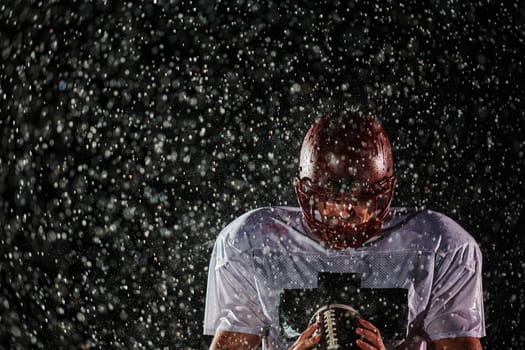 American Football Field: Lonely Athlete Warrior Standing on a Field Holds his Helmet and Ready to Play. Player Preparing to Run, Attack and Score Touchdown. Rainy Night with Dramatic Fog, Blue Light.