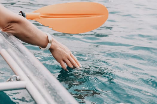 Woman in kayak back view. Happy young woman with long hair floating in transparent kayak on the crystal clear sea. Summer holiday vacation and cheerful female people having fun on the boat.