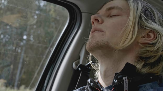 Young man with anxiety driving car. Stock. Close-up of man conveys emotions while driving car. Man with panic attack driving car on side of road.