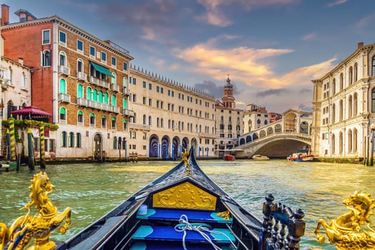 Panoramic view of famous Canal Grande with famous gondola and Rialto Bridge at sunset in Venice