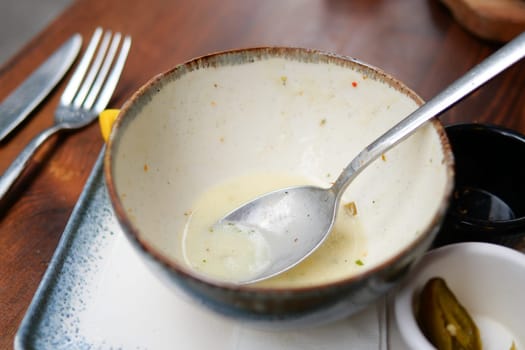 An empty dirty bowl with a spoon on a table