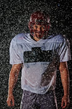 American Football Field: Lonely Athlete Warrior Standing on a Field Holds his Helmet and Ready to Play. Player Preparing to Run, Attack and Score Touchdown. Rainy Night with Dramatic Fog, Blue Light.